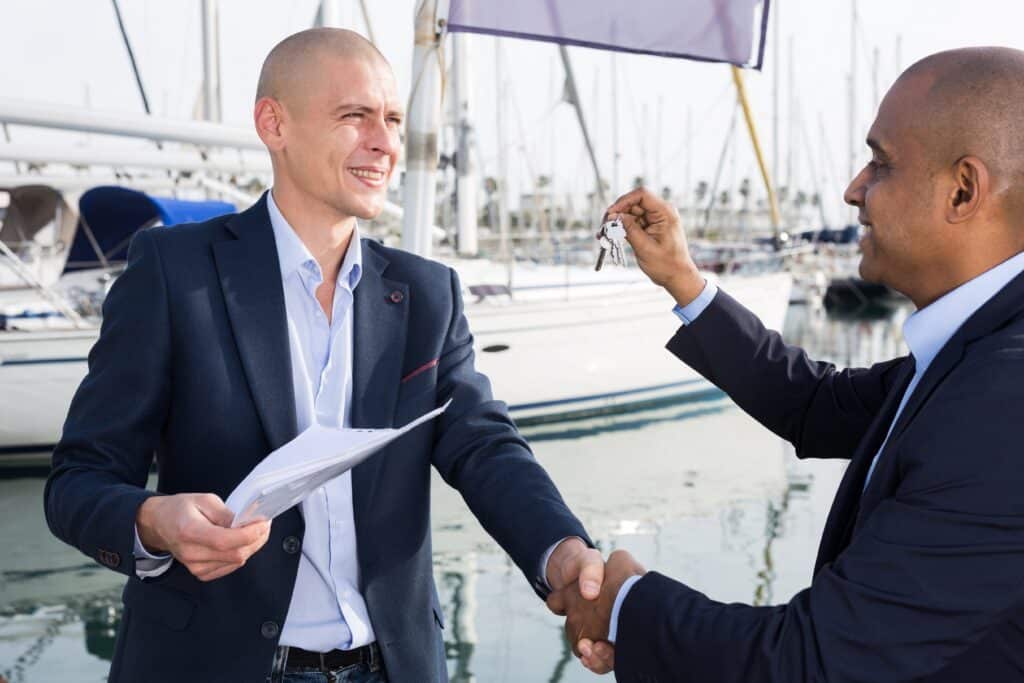 Un homme recevant les clés du bateau qu'il vient d'acheter en LOA