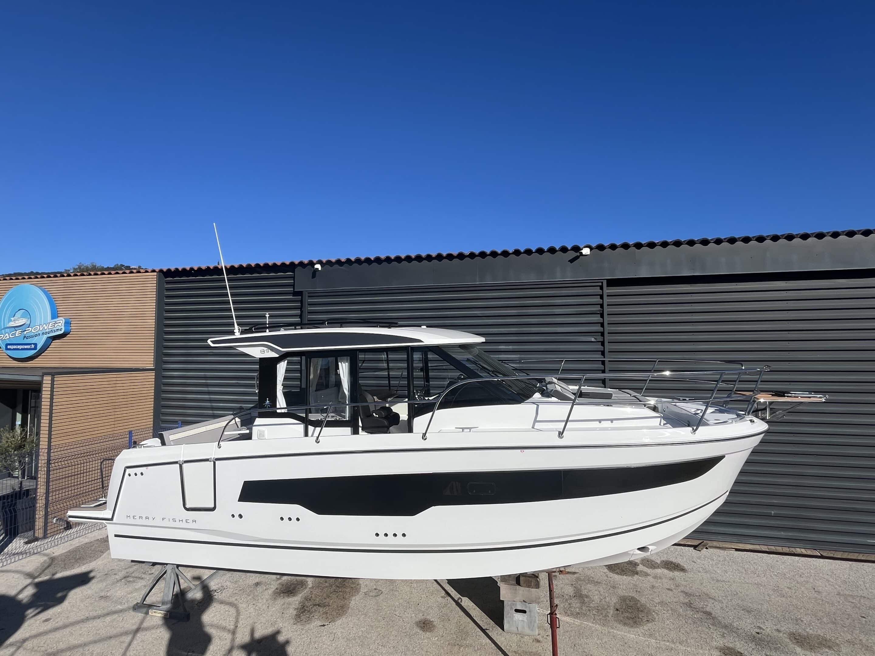 Bateau Merry Fisher 895 vu de profil à quai devant un bâtiment nautique