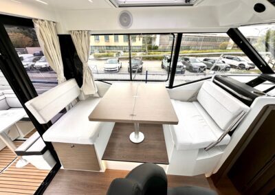 Salon intérieur du Merry Fisher 895 avec banquettes face à face et table centrale
