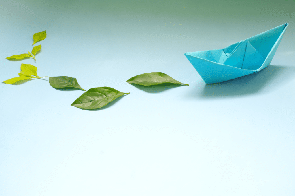Bateau en papier émettant des feuilles vertes fraîches